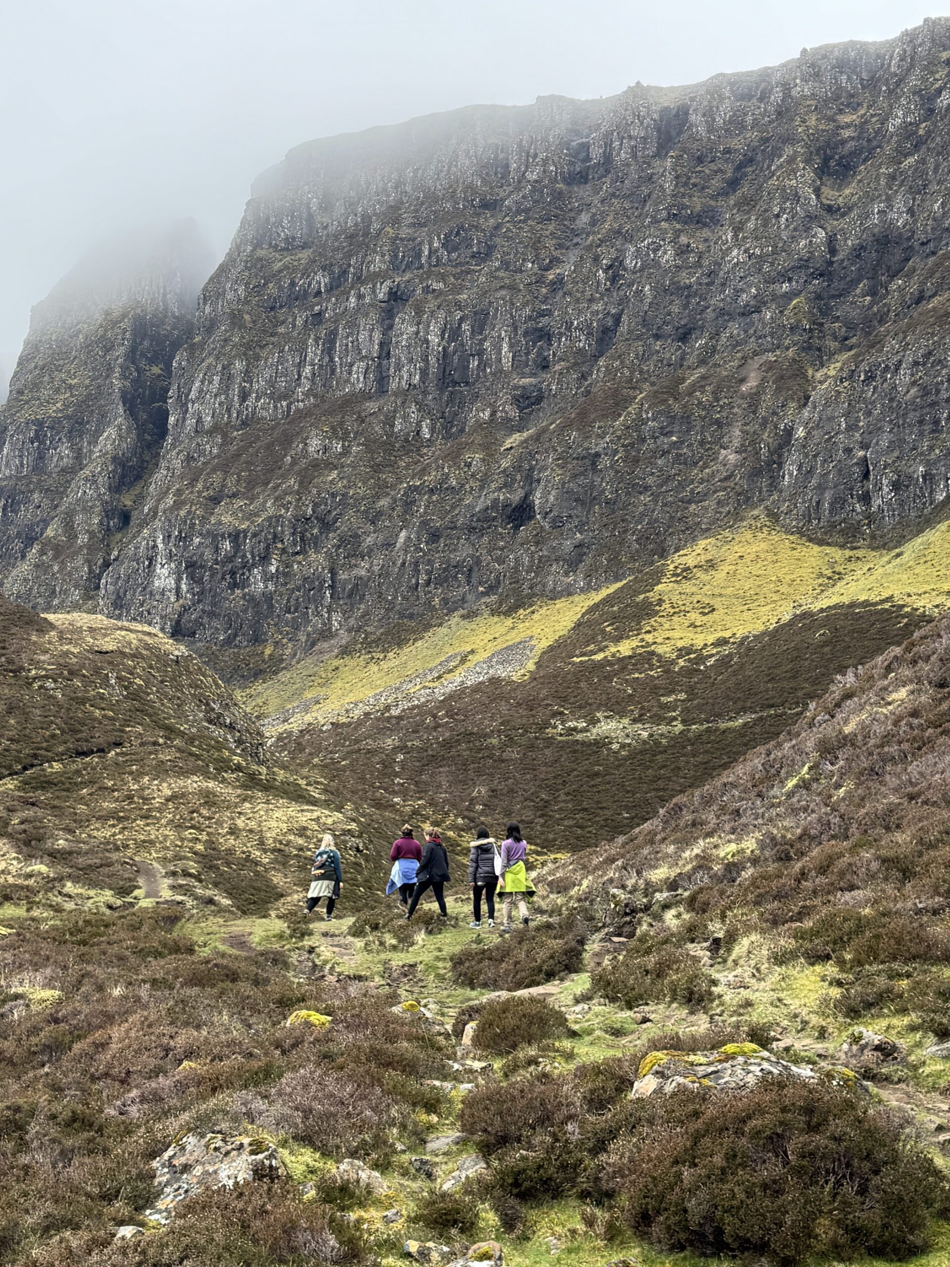 rugged landscape, Scottish terrain, group of hikers, rolling fog, misty mountains, Old Man of Storr, Isle of Skye