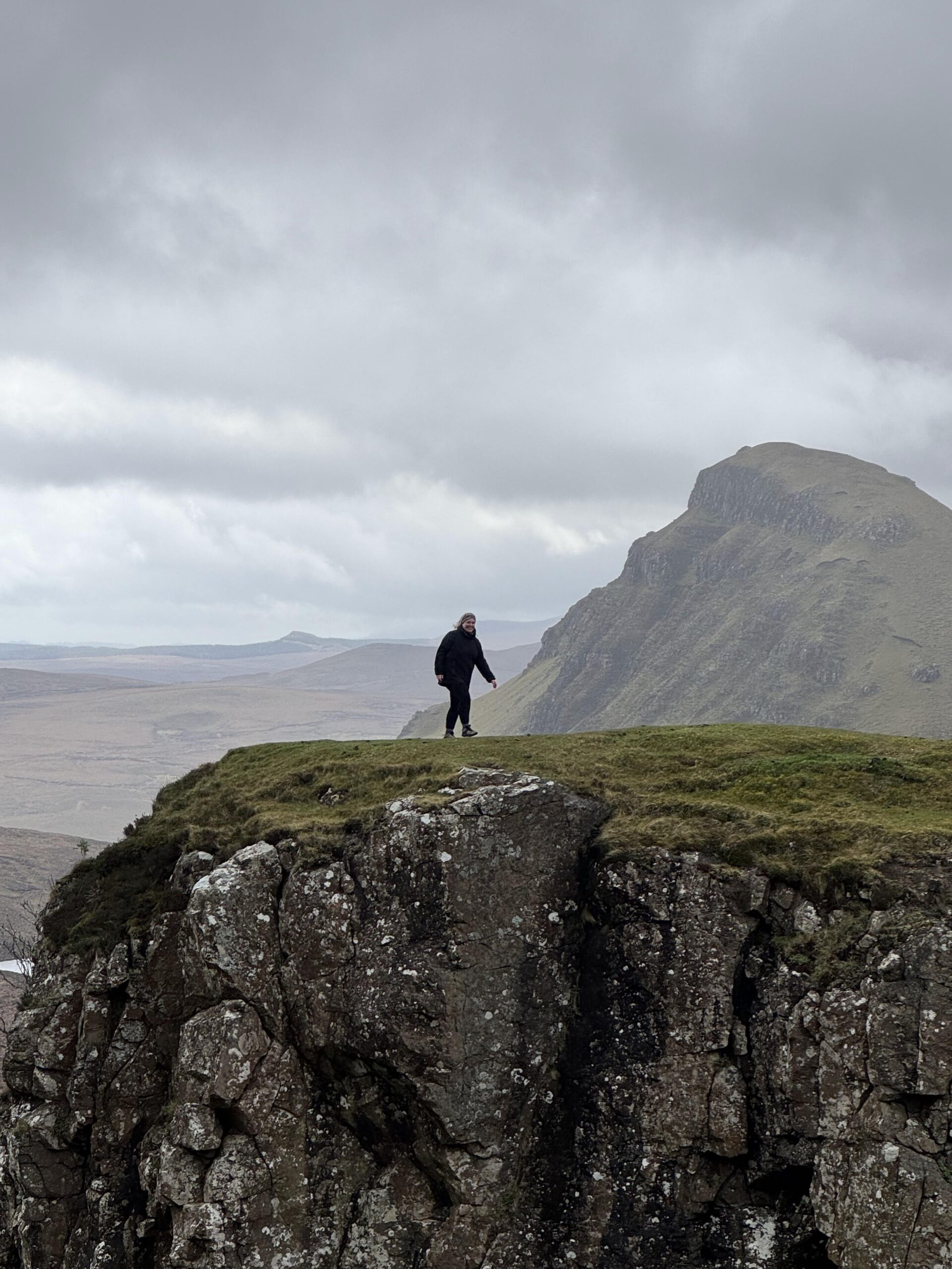Scottish highlands tour, woman hiking, moody landscape, walking on the cliff edge at the Quiraing on the Isle of Skye