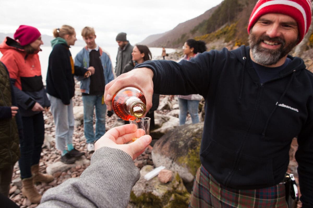 Tour guide providing Whisky on a group trip, Touring the Scottish Highlands, Meaningful Travel Experiences